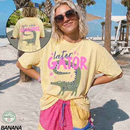 Person wearing a yellow 'Later Gator' t-shirt with a graphic of a gator on a beach.