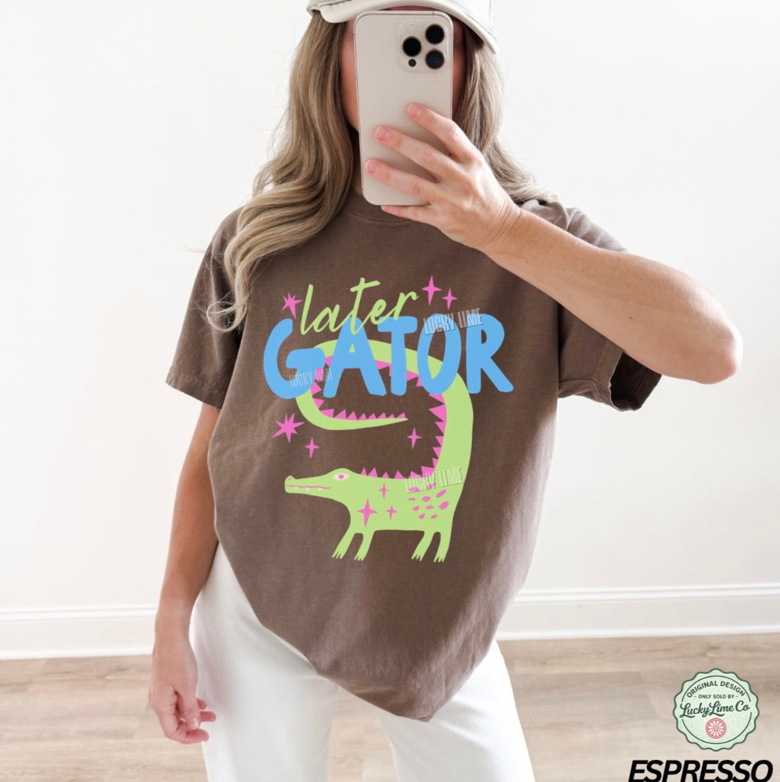 Person wearing a brown t-shirt with 'later GATOR' text and alligator graphic, taking a mirror selfie.