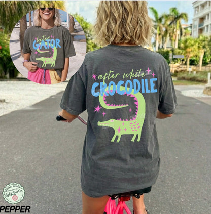 Person wearing a t-shirt with a crocodile graphic and text, standing outdoors.