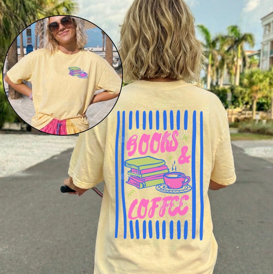Person wearing a yellow t-shirt with 'Books & Coffee' design, standing outdoors.