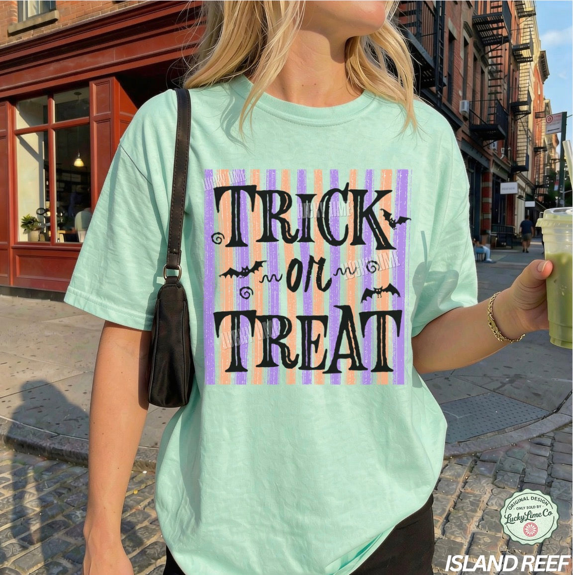 Person wearing a light green t-shirt with 'Trick or Treat' design on a city street.