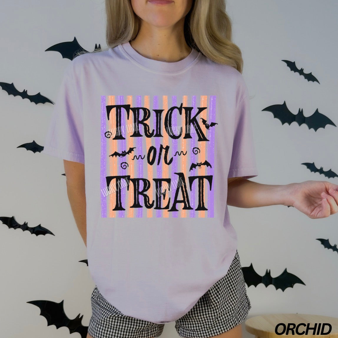 Person wearing a 'Trick or Treat' t-shirt with Halloween-themed decorations in the background.