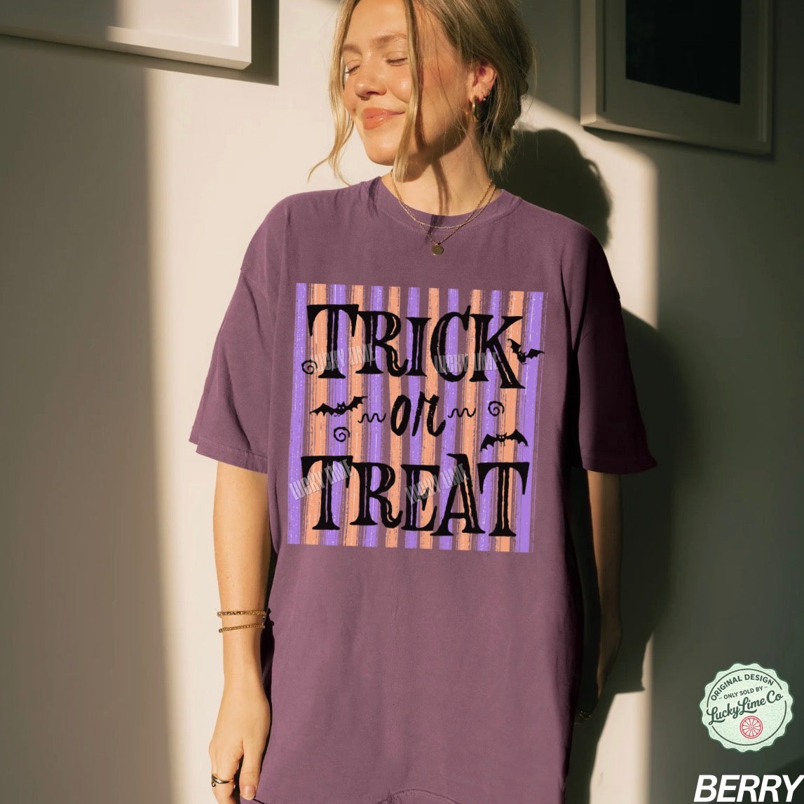 Person wearing a purple 'Trick or Treat' t-shirt against a neutral wall.