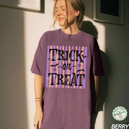 Person wearing a purple 'Trick or Treat' t-shirt against a neutral wall.