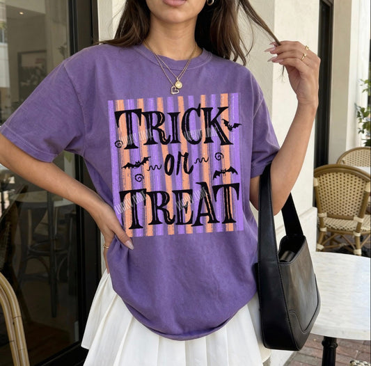 Person wearing a purple 'Trick or Treat' shirt outdoors.