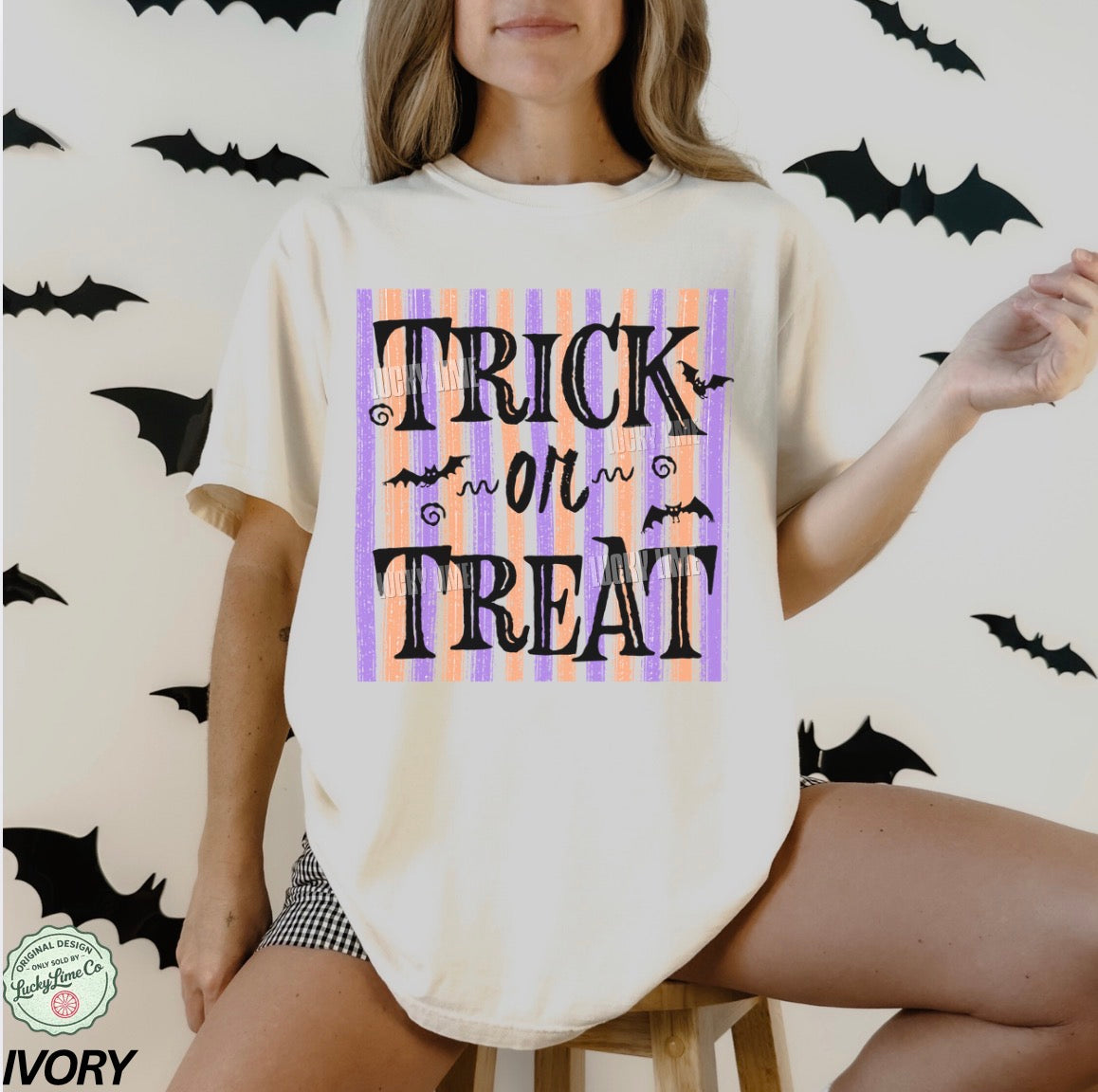 Person wearing a 'Trick or Treat' shirt with bats on a Halloween-themed background