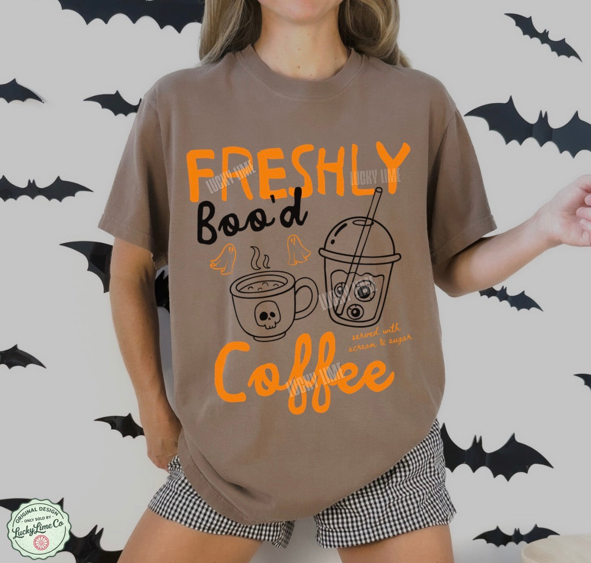 Person wearing a brown t-shirt with Halloween-themed coffee design and text on a bat-patterned background.