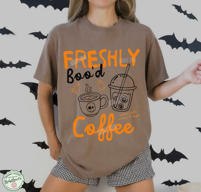 Person wearing a brown t-shirt with Halloween-themed coffee design and text on a bat-patterned background.