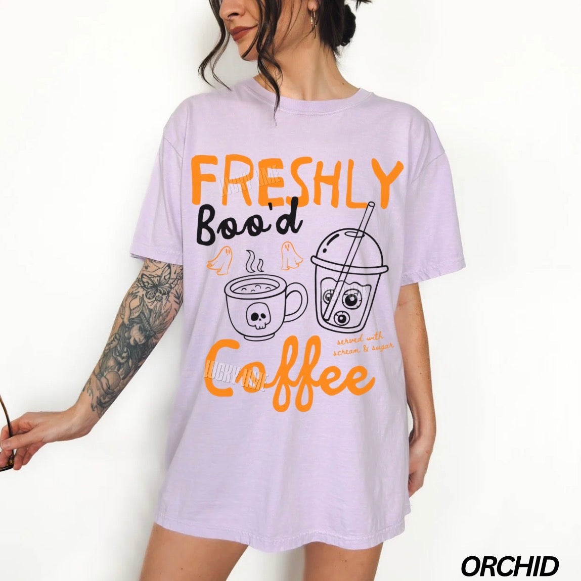 Person wearing a light purple t-shirt with coffee-themed graphics and text.