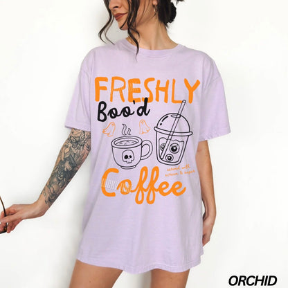 Person wearing a light purple t-shirt with coffee-themed graphics and text.