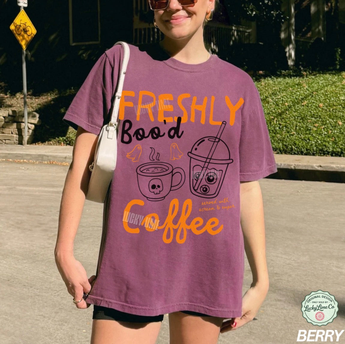 Person wearing a purple t-shirt with orange text and graphics, standing outdoors.