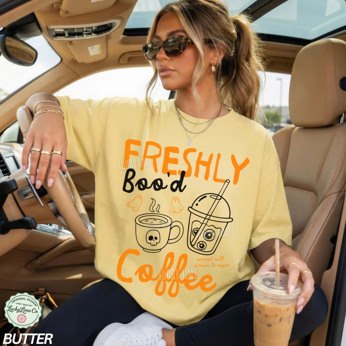 Woman sitting in a car wearing a yellow t-shirt with coffee-themed text and graphics.