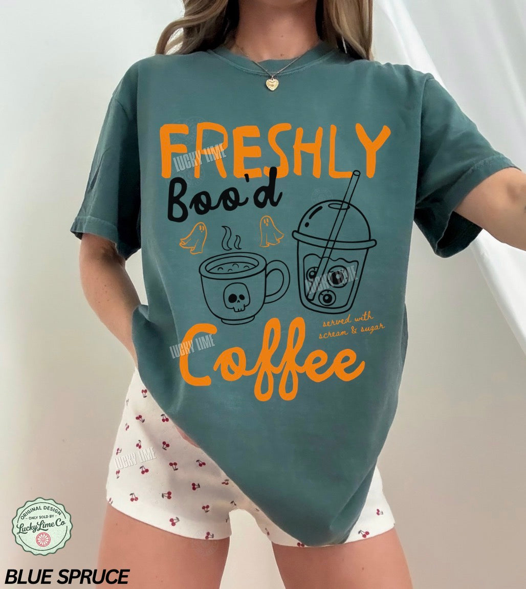 Person wearing a teal t-shirt with coffee-themed design and white shorts.