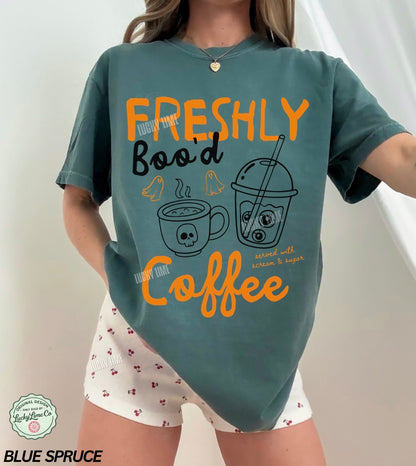 Person wearing a teal t-shirt with coffee-themed design and white shorts.