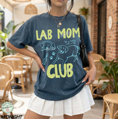 Person wearing a blue t-shirt with 'Lab Mom Club' design in a casual setting.