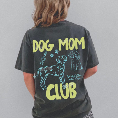 Person wearing a dark grey  t-shirt with 'Dog Mom Club' text and dog illustrations on the back, standing against a gray background.