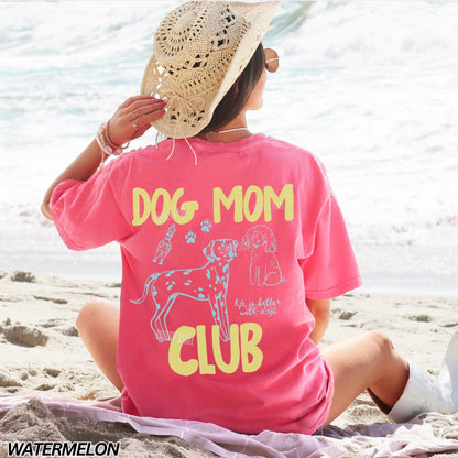 Person wearing a pink 'Dog Mom Club' t-shirt on a beach.