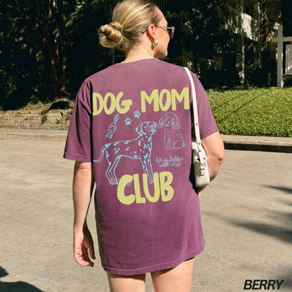 Person wearing a purple t-shirt with 'Dog Mom Club' text and graphics outdoors.