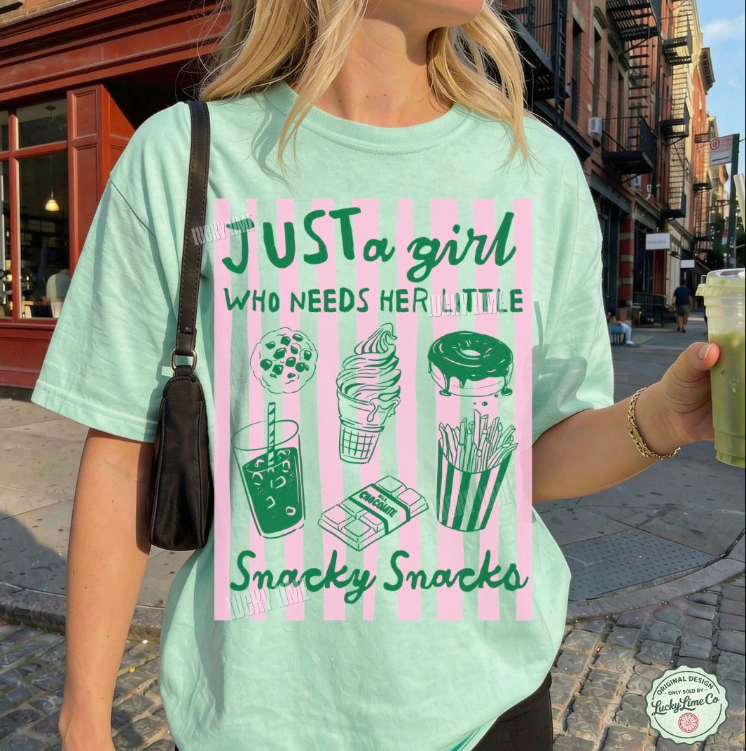 Person wearing a light green t-shirt with a graphic design and text on a city street.