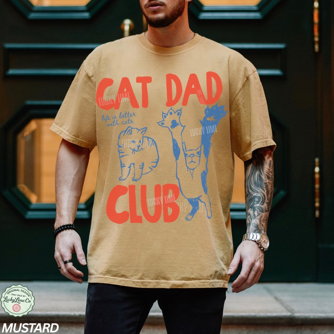 Man wearing a beige t-shirt with 'Cat Dad Club' design in front of a dark door.