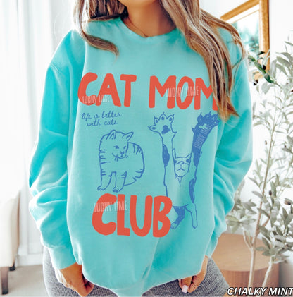 Person wearing a light blue sweatshirt with 'Cat Mom Club' text and graphics.