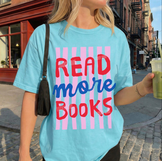 Person wearing a light blue t-shirt with 'READ more BOOKS' text on a city street.
