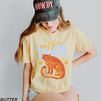 Person wearing a yellow t-shirt with a tiger graphic and 'easy tiger' text, paired with a 'HOWDY' cap.