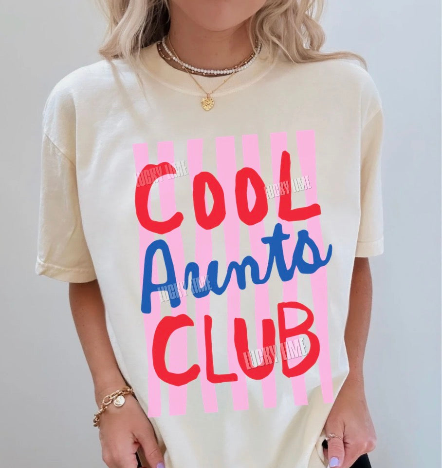 Woman wearing and ivory colored shirt with pink striped design that says “cool aunts club”