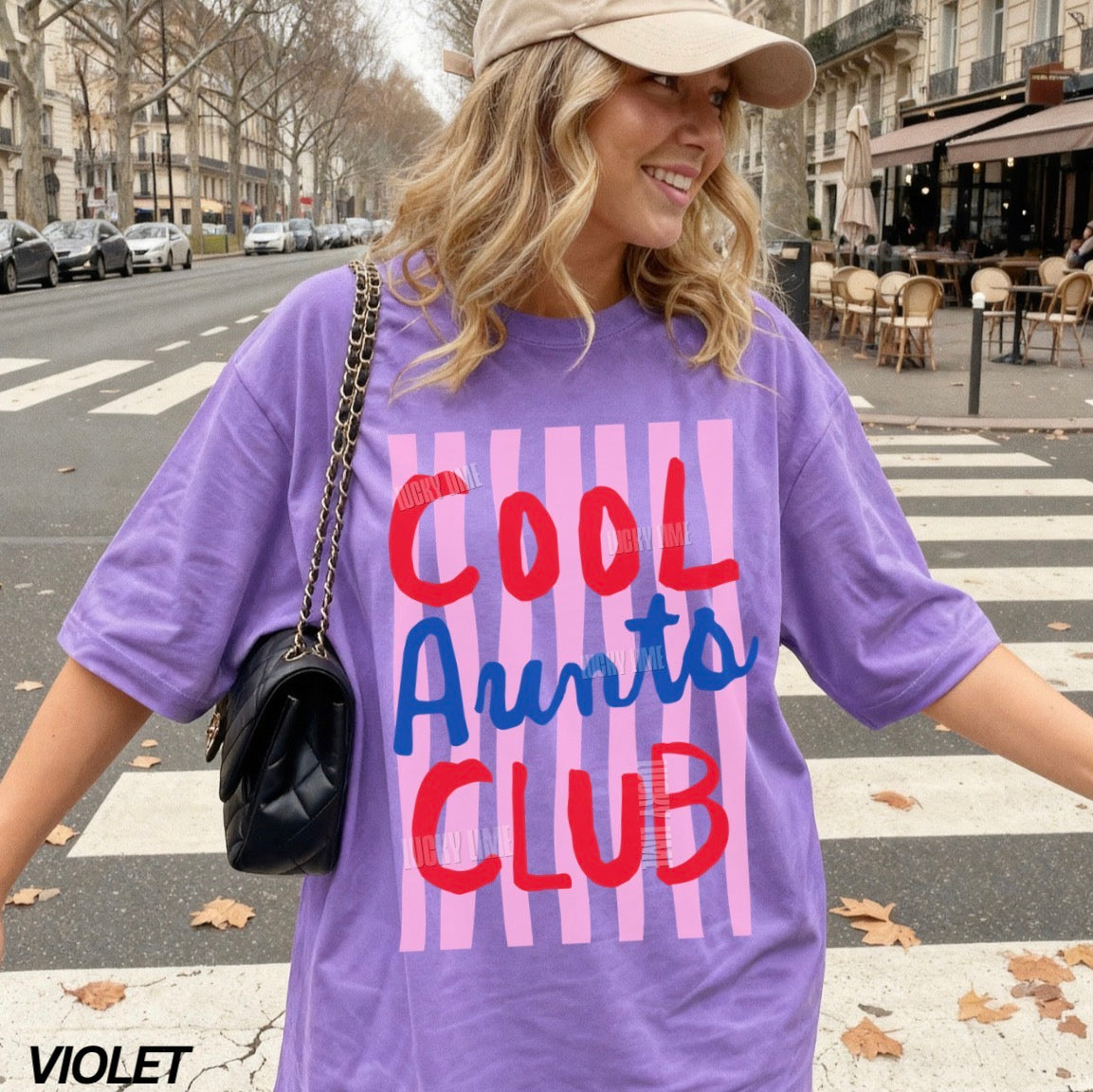 Woman wearing and violet colored shirt with pink striped design that says “cool aunts club”