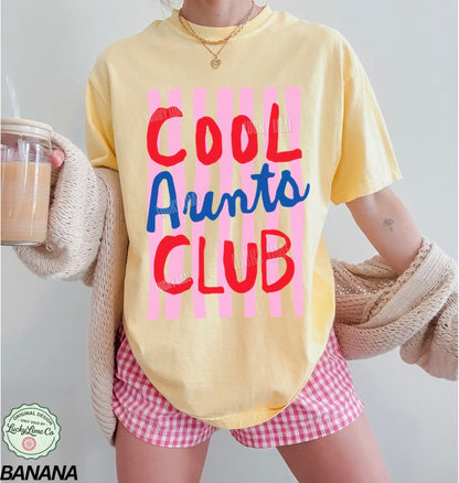 Woman wearing and banana yellow colored shirt with pink striped design that says “cool aunts club”