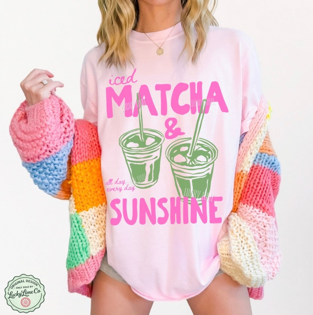 Person wearing a pink sweatshirt with 'iced matcha & sunshine' text and colorful sleeves.