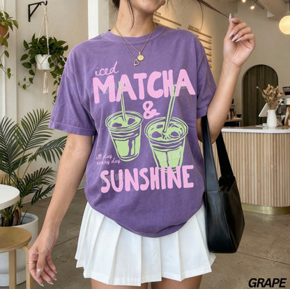 Person wearing a purple t-shirt with 'iced matcha & sunshine' text in a casual setting.