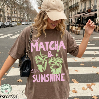 Woman wearing a brown t-shirt with matcha and sunshine text on a city street.