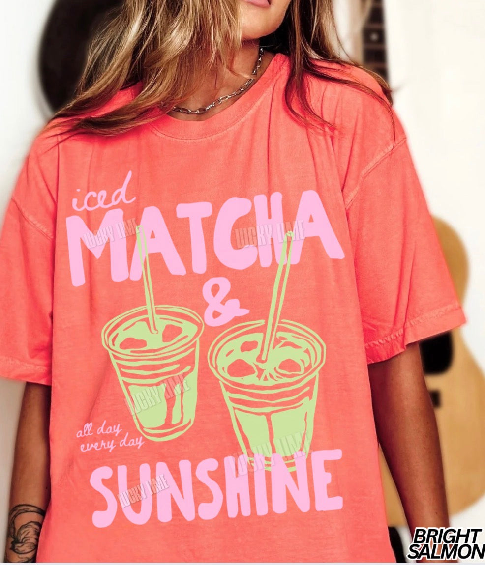 Person wearing a pink t-shirt with 'iced matcha & sunshine' text and graphics.