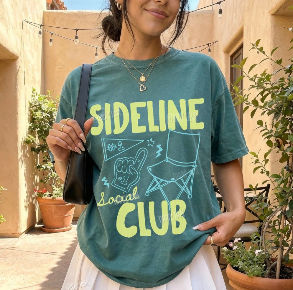 Woman wearing a green t-shirt with 'Sideline Social Club' design outdoors.