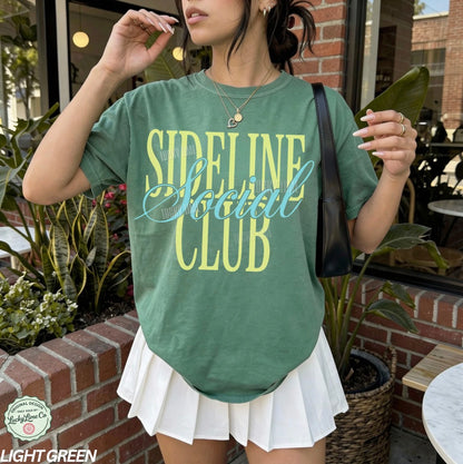 Person wearing a green 'Sideline Social Club' t-shirt outdoors.