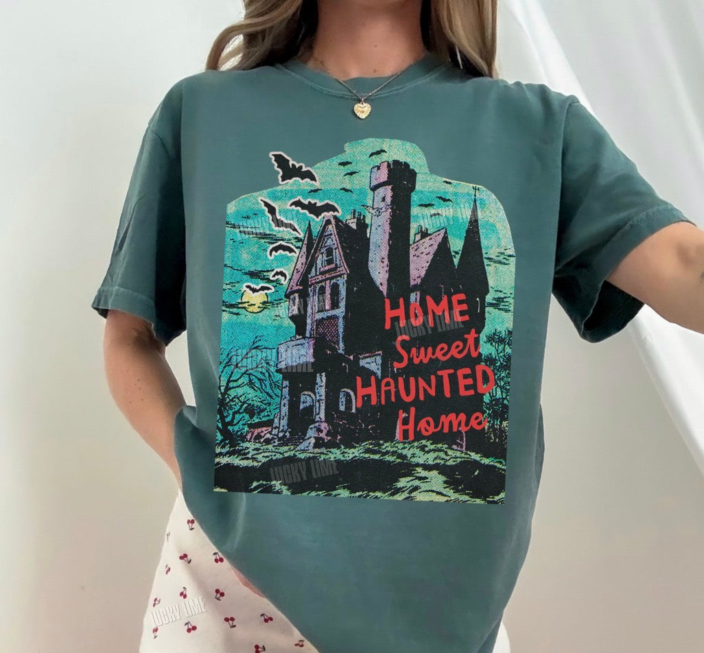 Person wearing a green t-shirt with a haunted house design and text.