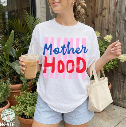 Person wearing a white t-shirt with 'Mother Hood' text, holding a drink and a bag outdoors.