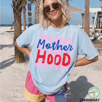 Person wearing a light blue t-shirt with 'Mother Hood' printed on it at a beach.
