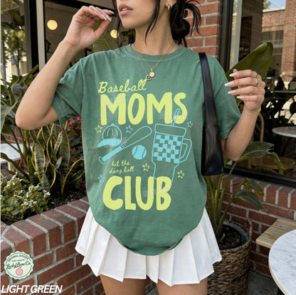 Person wearing a green t-shirt with 'Baseball Moms Club' text and graphics outdoors.