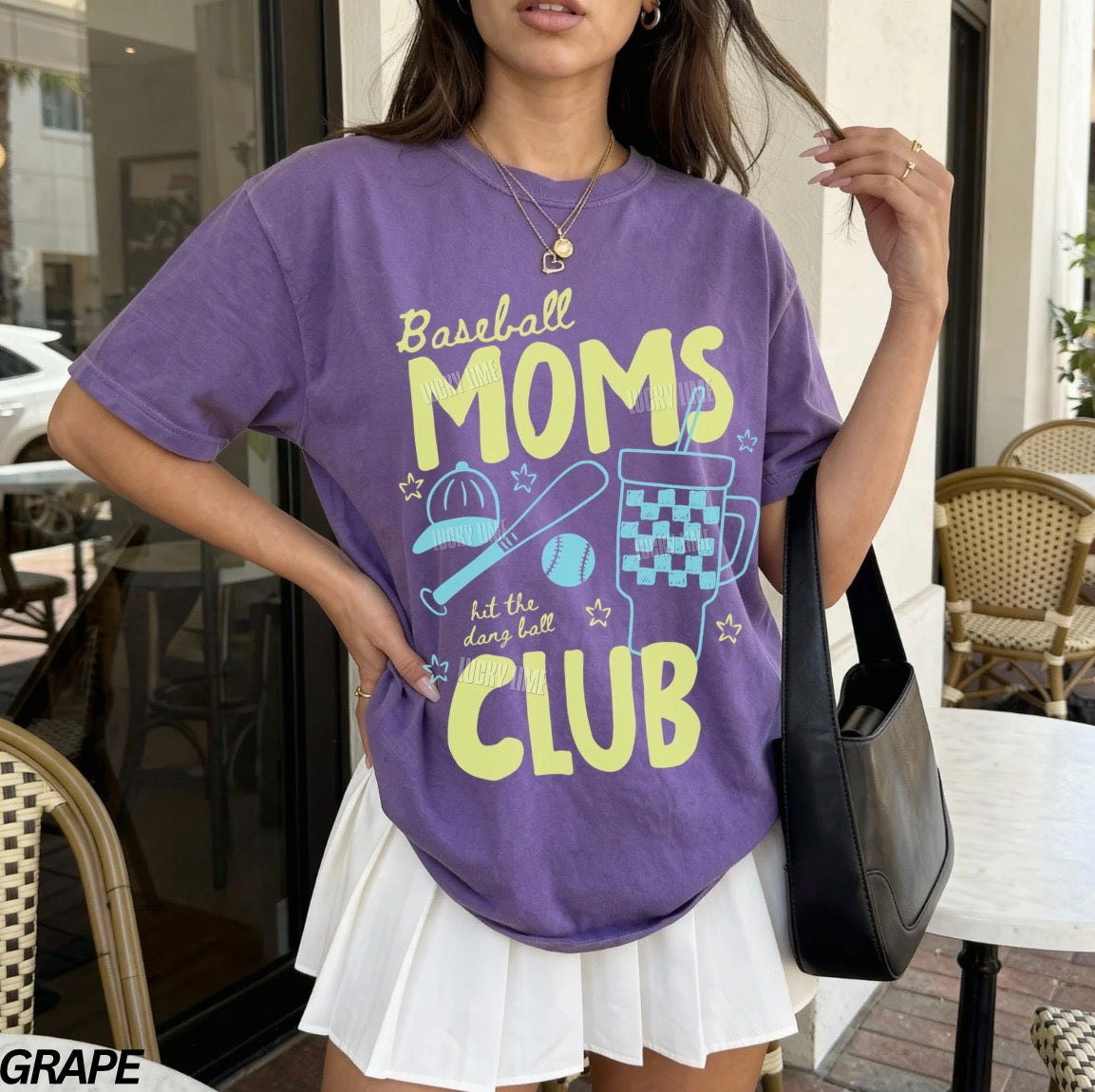 Woman wearing a purple t-shirt with 'Baseball Moms Club' text and graphics, standing outdoors.