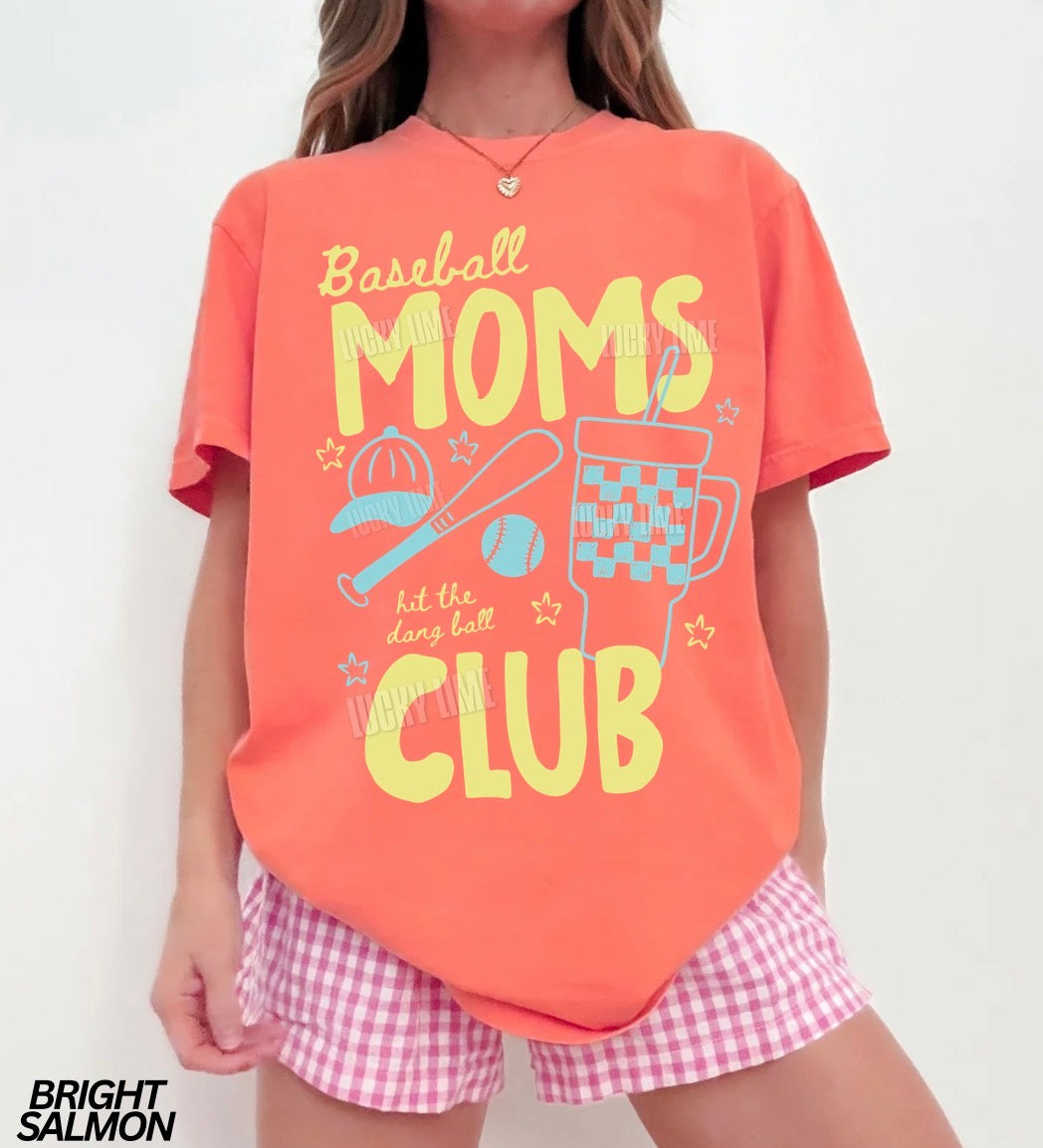 Person wearing a bright salmon t-shirt with 'Baseball Moms Club' text and pink checkered shorts on a white background.