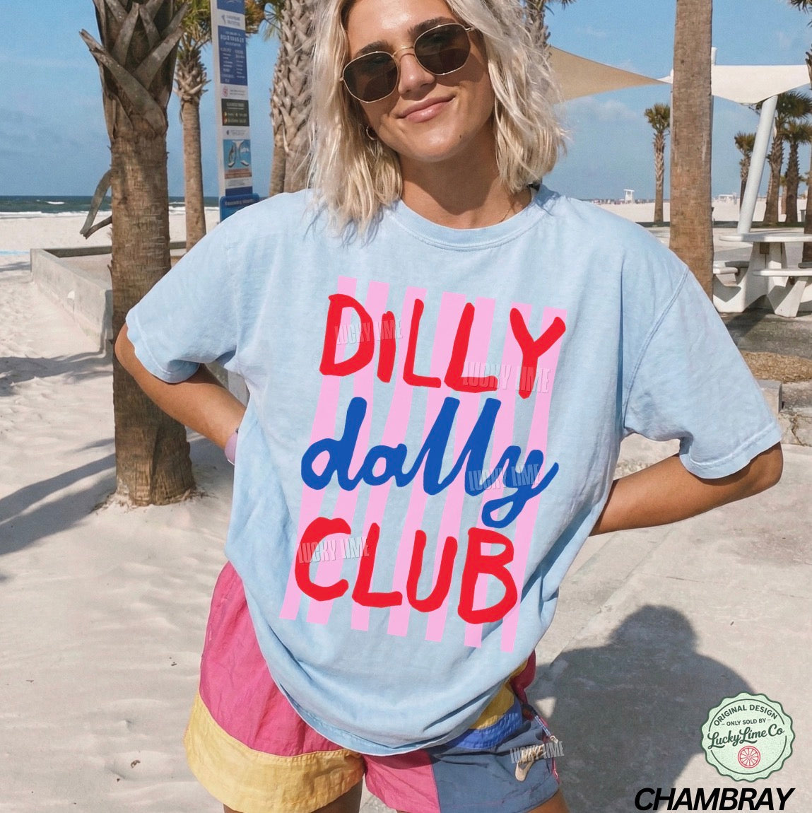 Person wearing a 'Dilly Dally Club' t-shirt on a beach.