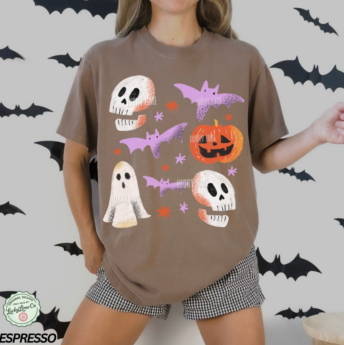 Person wearing a brown t-shirt with Halloween-themed graphics on a white background with black bats.