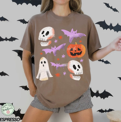 Person wearing a brown t-shirt with Halloween-themed graphics on a white background with black bats.