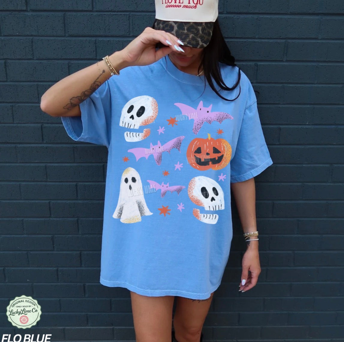 Person wearing a blue Halloween-themed t-shirt against a dark brick wall.