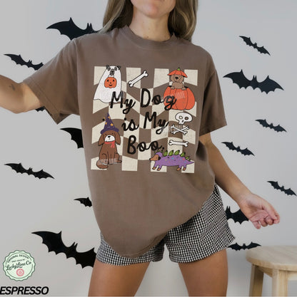 Person wearing a brown t-shirt with Halloween-themed design and checkered shorts, surrounded by black bats.