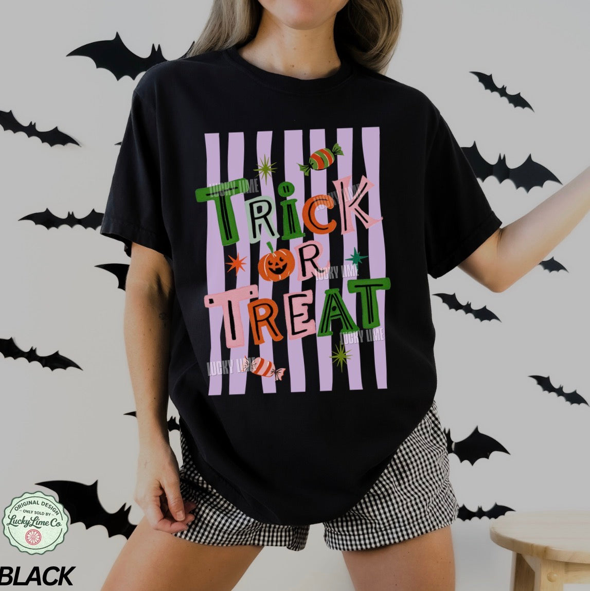 Person wearing a black 'Trick or Treat' Halloween shirt with bats in the background