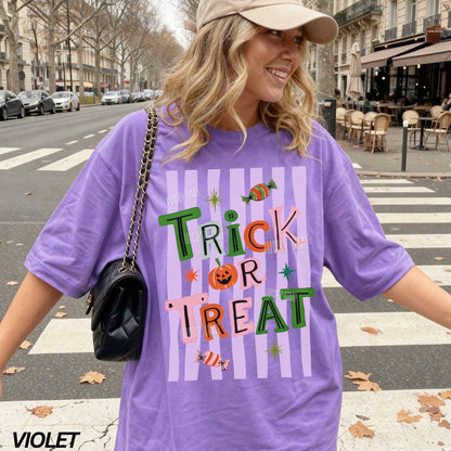 Woman wearing a purple 'Trick or Treat' t-shirt on a city street.