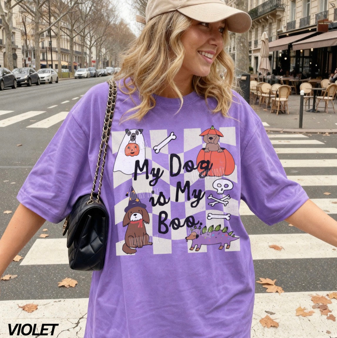 Person wearing a purple t-shirt with dog-themed design on a city street.